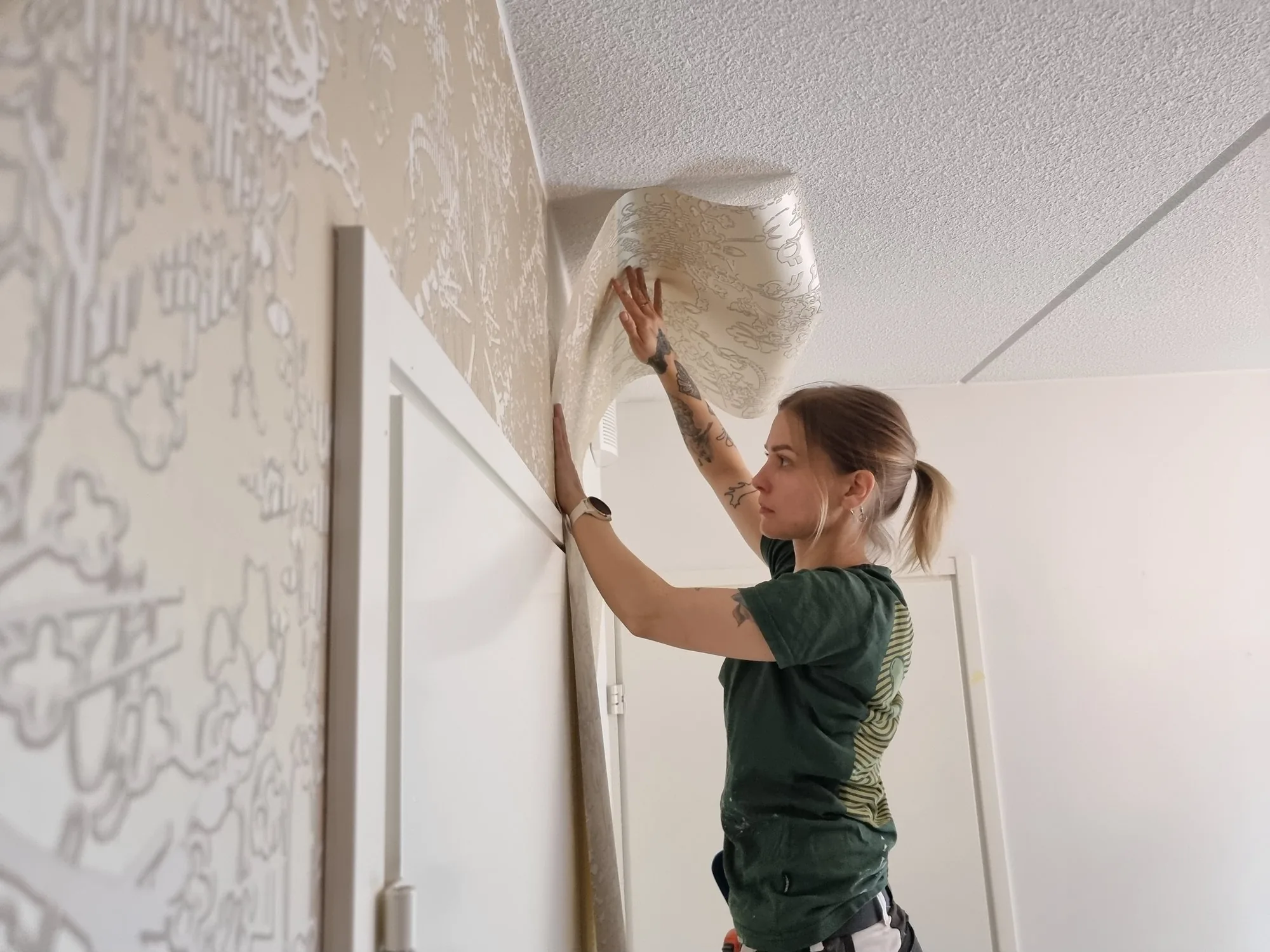 Netta laittaa tapettia seinään. Hän on FoxDon kautta tilattava pintakäsittelyjen ammattilainen